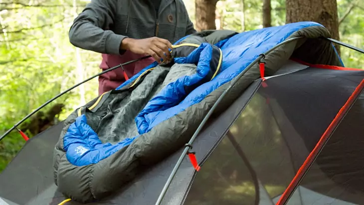 A man fixing a sleeping bag on a tent
