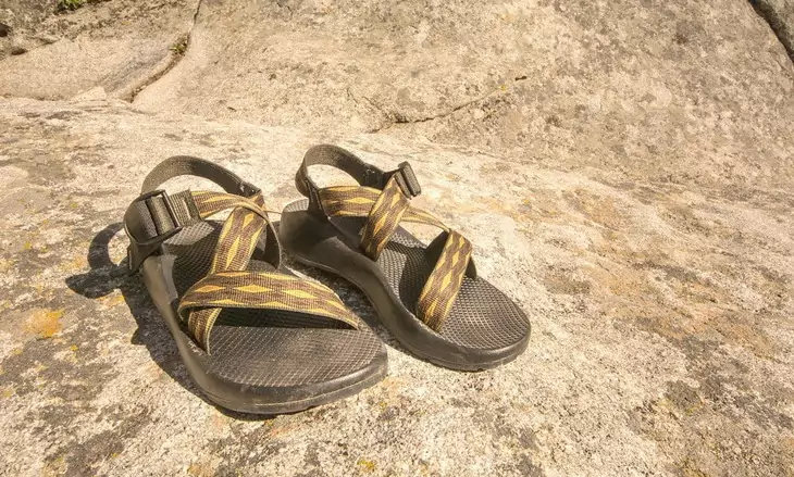 a pair of sport hiking sandals sitting on the ground in the sun