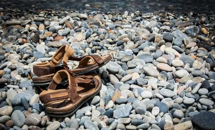 A pair of sandals of rocks near a water