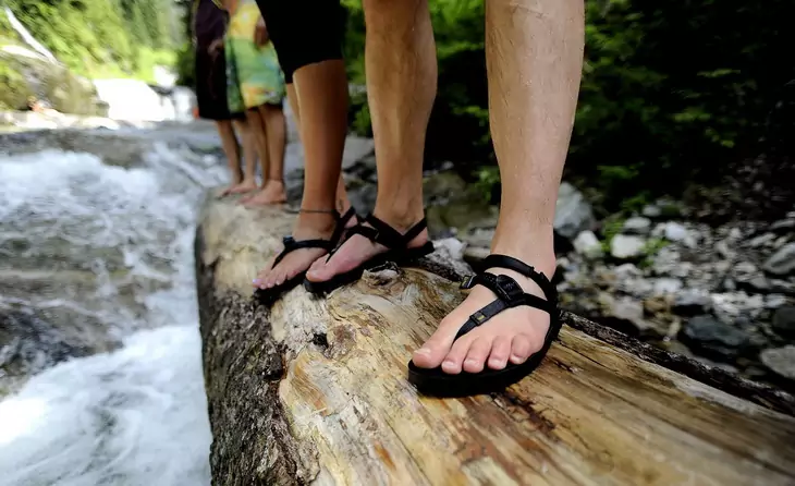 Image of a man legs wearing a pair of sport sandals while hiking