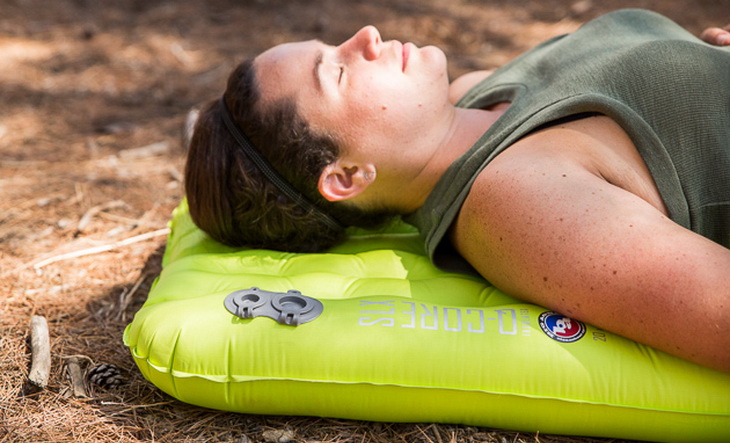 A woman relaxing on a sleeping air pad in the forest