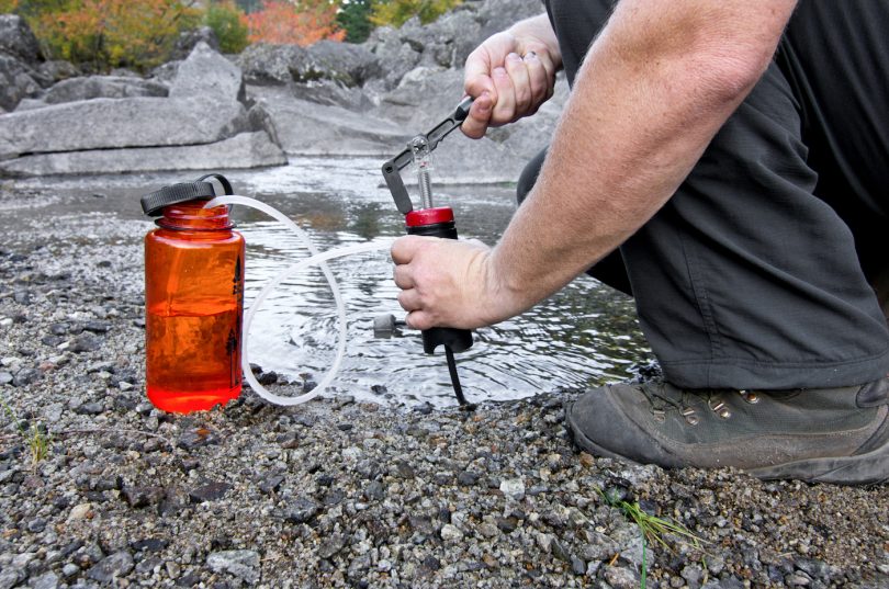 A person uses a lightweight compact water filter to pump safe drinking water