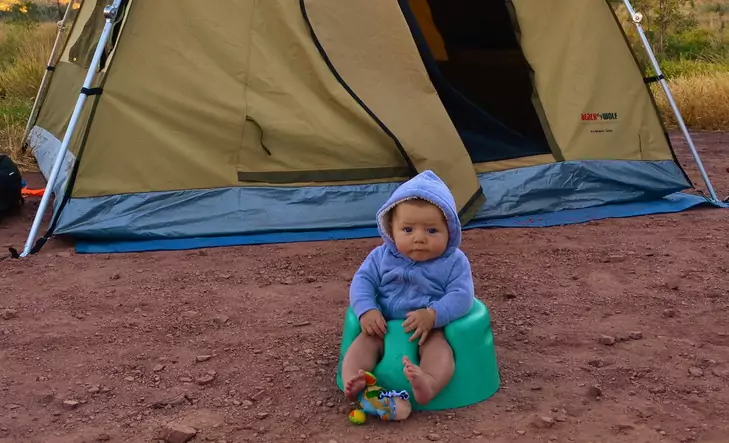 Little baby sitting on a seat in front of a tent