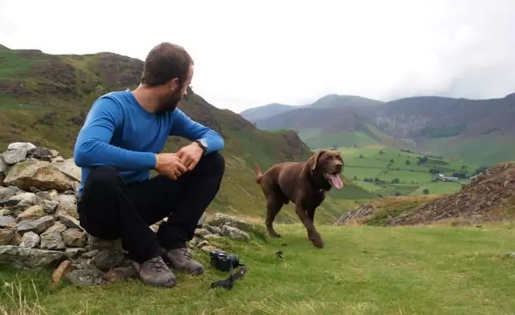 A man wearing a base layer is looking at his dog