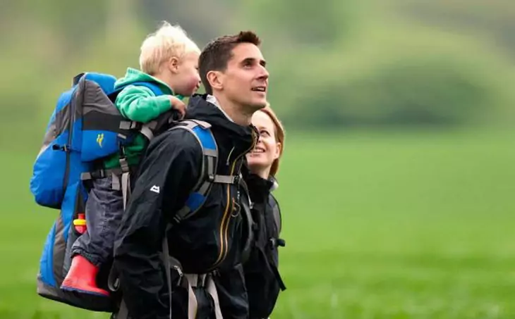 two adults hiking with their baby