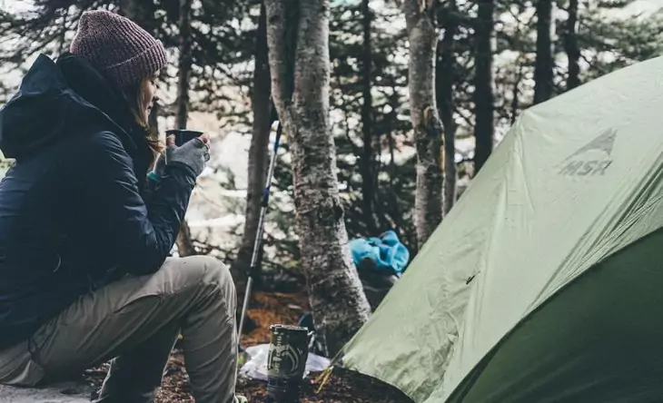 Woman hiker enjoying a cup of coffee and peace around her