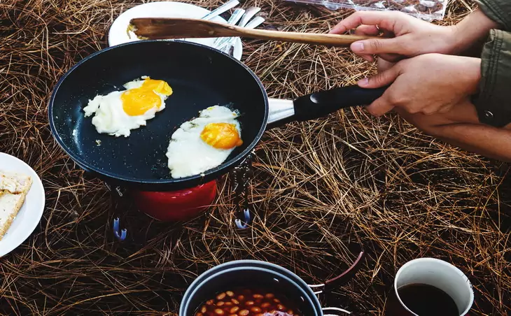 A man cooking eggs on a backpacking frying pan