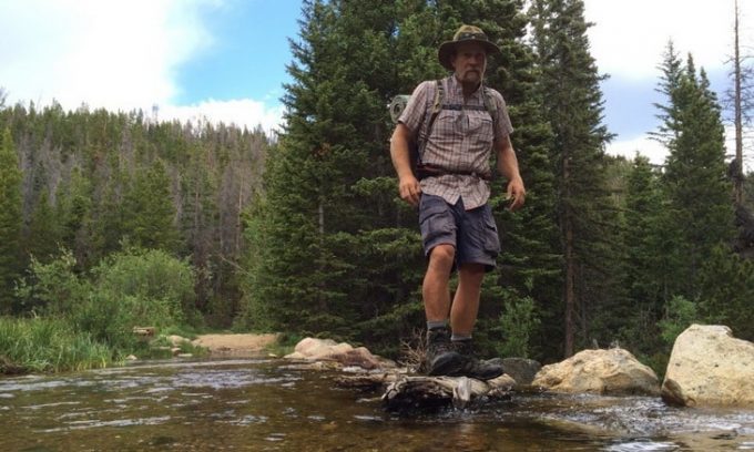 man with backpack crossing stream