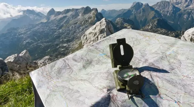 Image showing a compass on a map and a moutain landscape