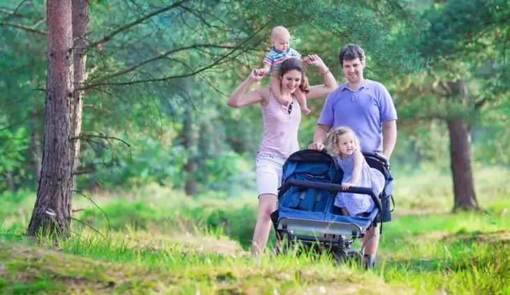 Active-parents-hiking-with-two-kids-in-a-stroller.