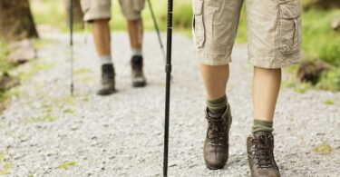 Low section of male and female hikers walking in shorts with trekking poles