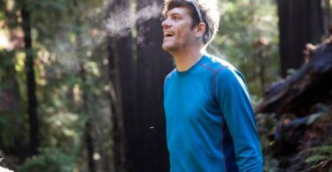 A man wearing Capilene Midweight is laughing in the wood