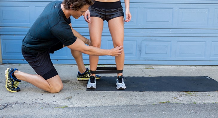 man showing a woman how to exercise with band walks