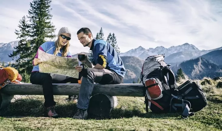 Couple hikers with map in mountains