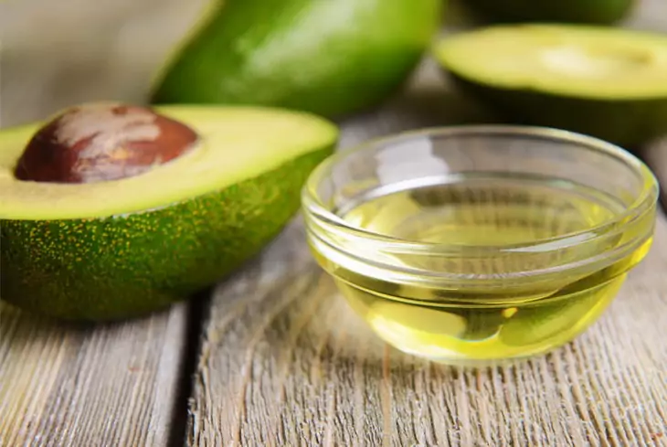 avocado oil near to avocado on the table