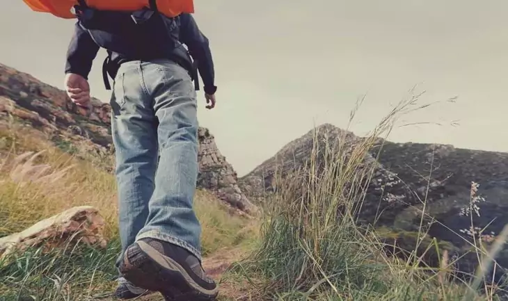 Man with a backpack hiking in jeans and boots