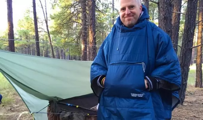 A man in the forest wearing a blue honcho-poncho