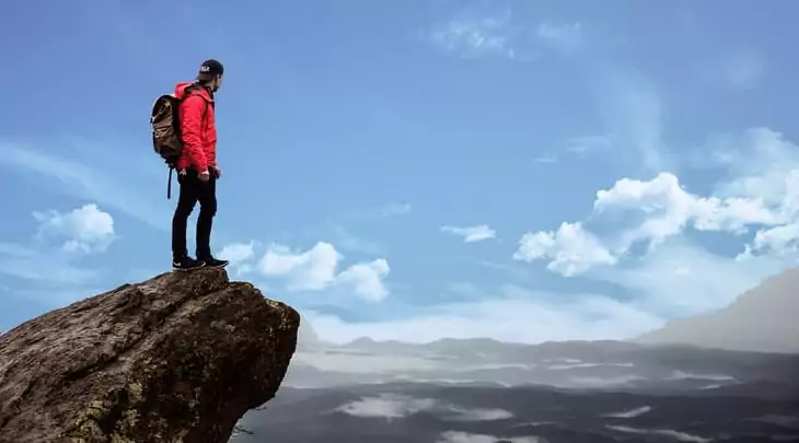 hiker sttting on a rock and watching the landscape