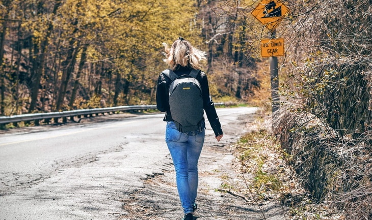 Young woman in jeans walking on a road