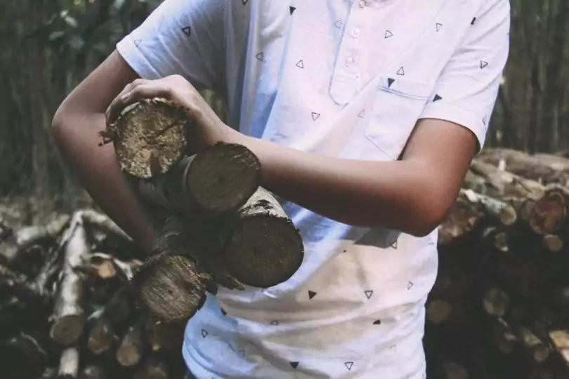 Man in White Polo Shirt Carrying on His Right Firewood Sticks