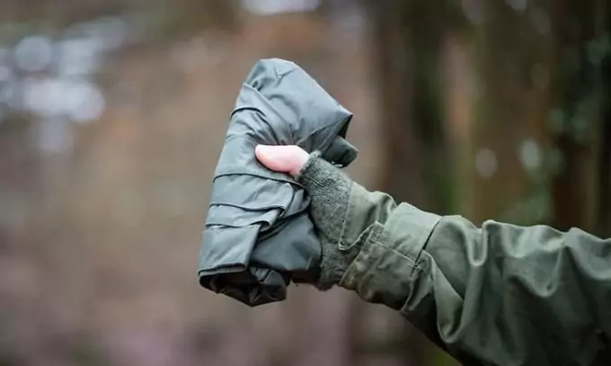 A man holding in his hands a packed poncho