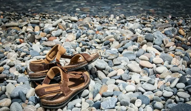 A pair of hiking sandals for womens on rocks near a water