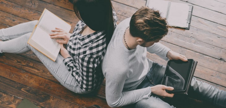 A couple reading books on the floor