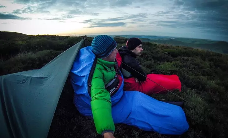 Two mens sitting in sleeping bags at down