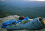Person in a sleeping bag on top of the mountains