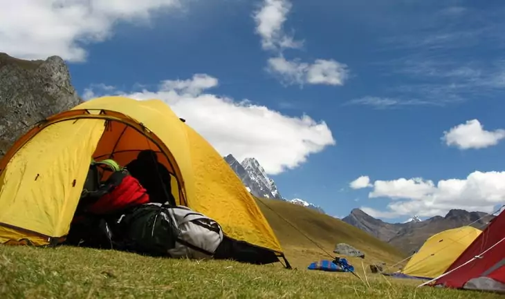 three tents in the picture and moutains in the background