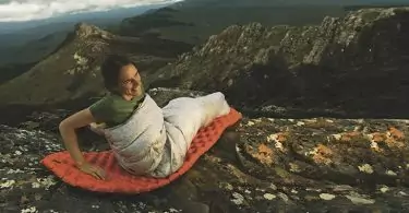 A woman sitting on Sea to Summit Ultralight Mat on top of the mountains