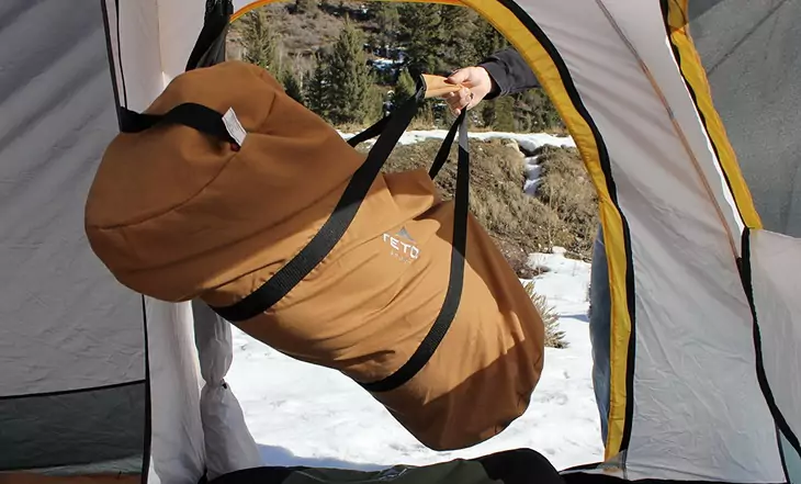 A person holding a Teton Sports Deer Hunter sleeping bag in a tent