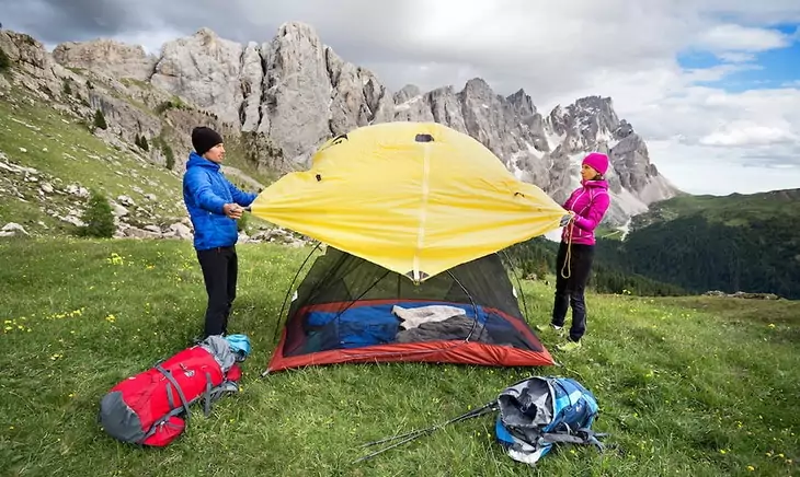 Couple setting up a tent and putting on the rainfly