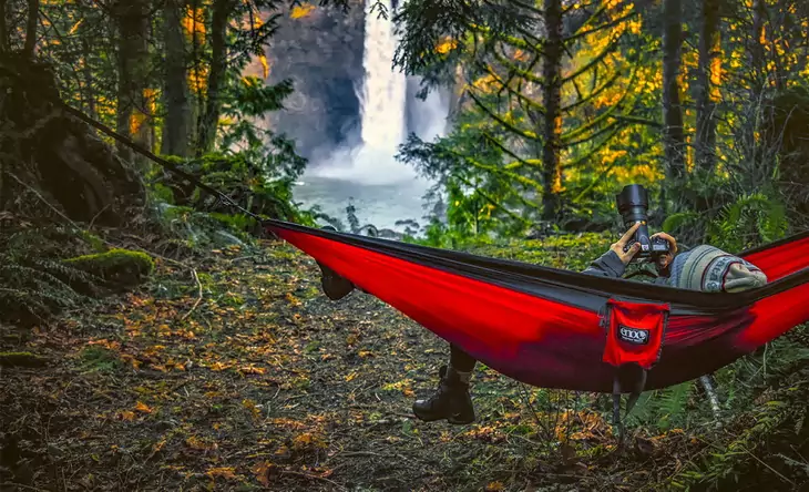 Man looking at his camera in Eagles Nest Double Hammock