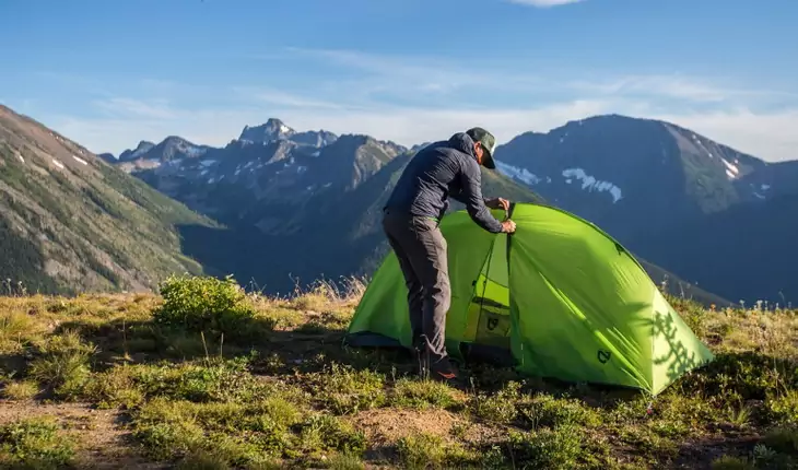 A man setting up the Nemo Hornet 2P tent in the mountains