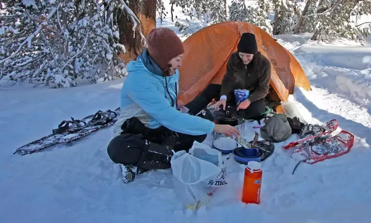 Two woman cooking in the snow