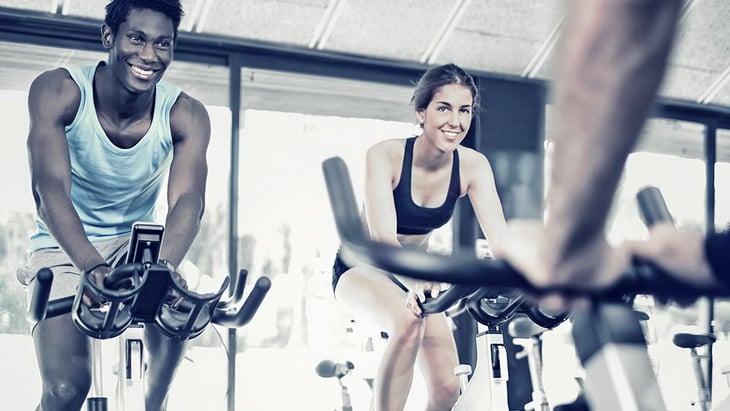 Two people doing an indoor cycling fitness class