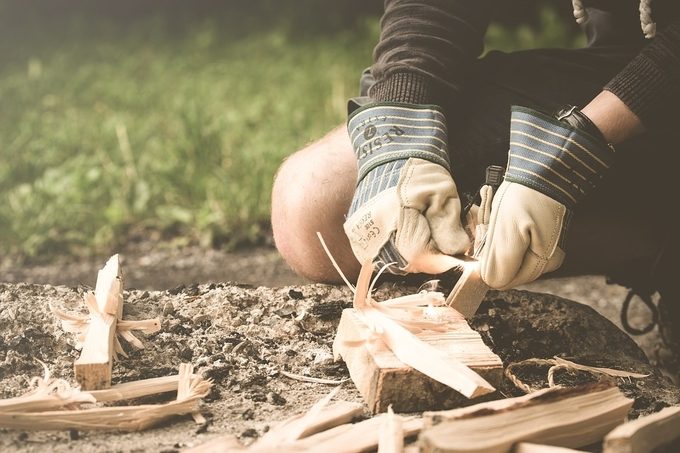 A man cutting tindersticks for starting a fire