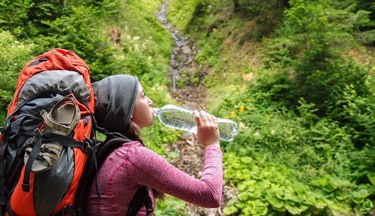 Woman hiker driking water from a bottle