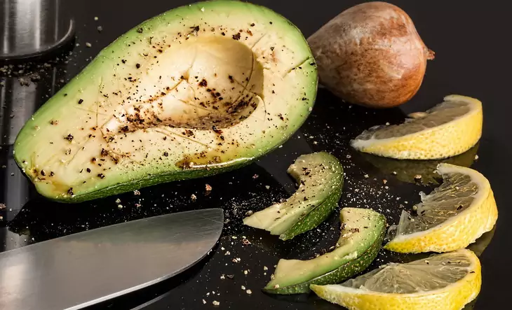 Half of avocado and few slices of lemon on the table