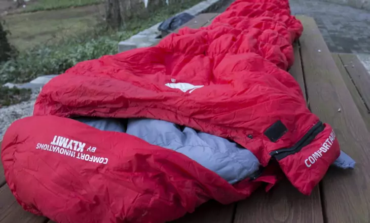 Man in Klymit KSB 20 Sleeping Bag laying on a table outside