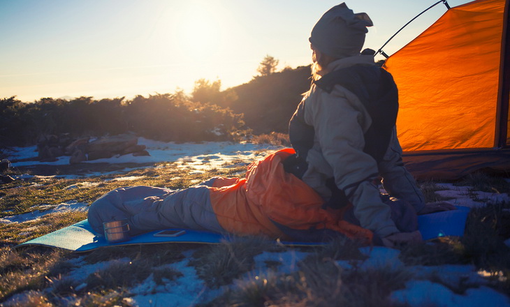 Woman in a sleeping bag looking at the sun