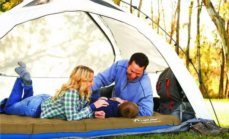 family-relaxing-in-the-tent sitting on a camping bed
