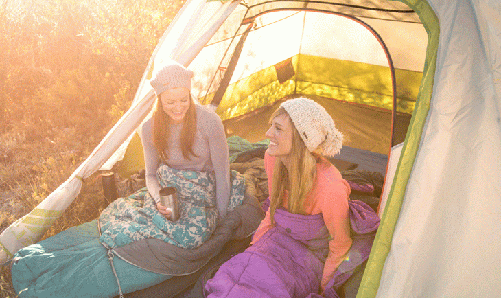 Two persons in A woman in the forest holding Kelty sleeping bag sleeping bags laughing in the wild