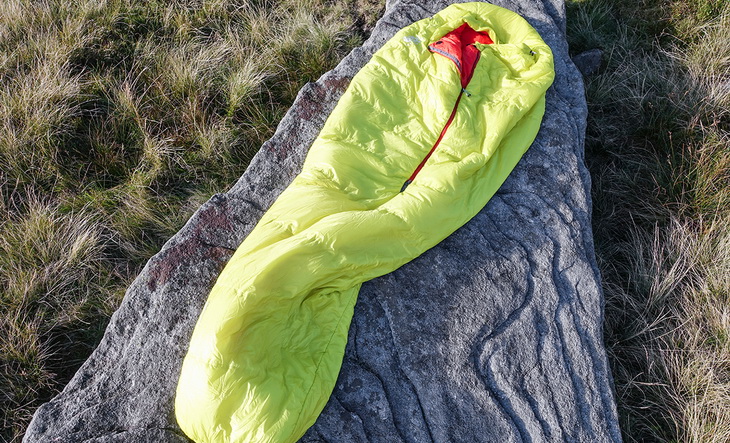 Two adults in Mountain Hardwear HyperLamina Spark 35 Sleeping Bags looking at the landscape on a rock