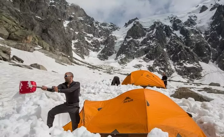 Man moving the snow near a tent