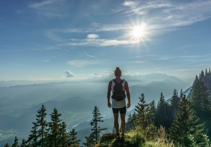 A hiker on the top of a mountain under the sun