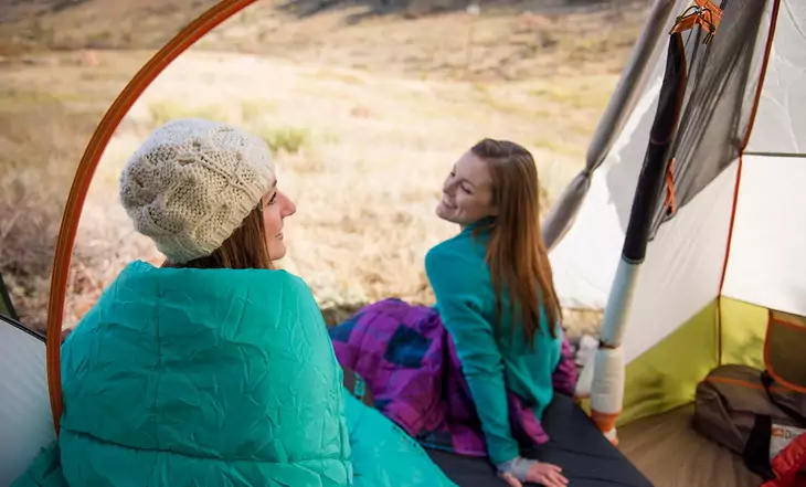 Two womens in sleeping bags laughing 