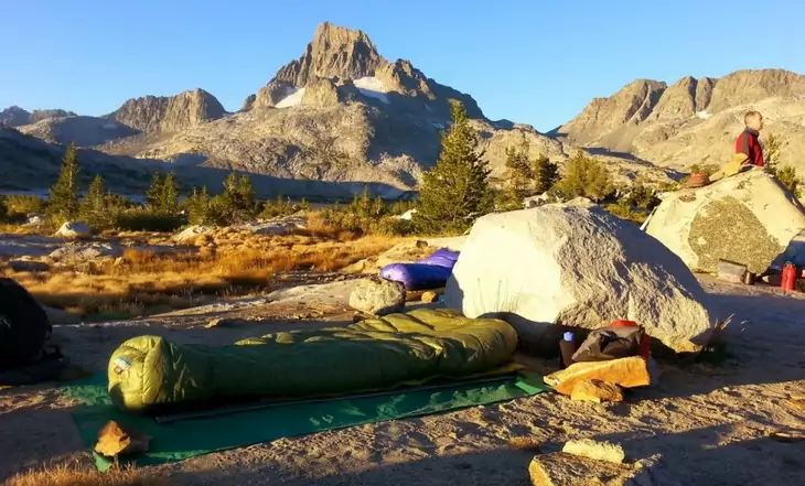 Western Mountaineering sleeping bag on the ground and mountains in the background