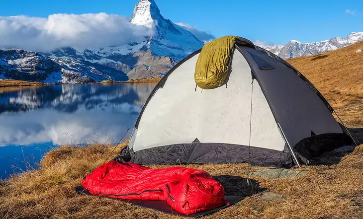 Two sleeping bags, a tent and the mountains in the background